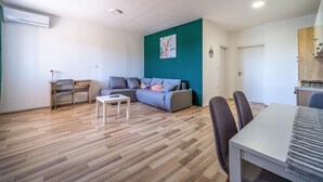 En moderne stue med en grå sofa, et lille hvidt bord og et spiseområde med stole.