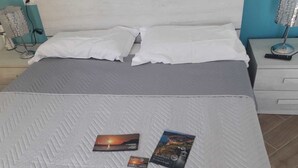 Una cama bien hecha con un edredón gris, dos almohadas y dos libros sobre la cama.