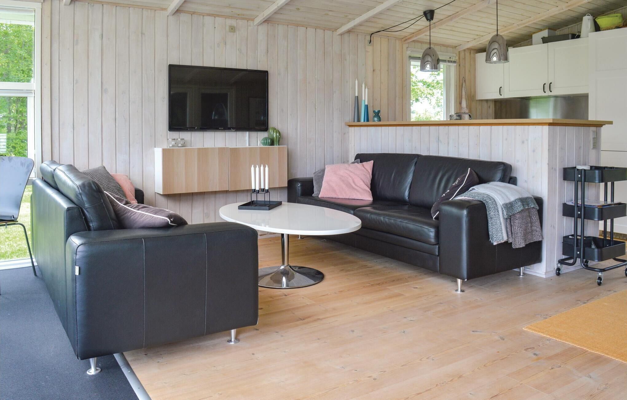 A modern living room with a black leather sofa, a white coffee table, and a TV mounted on the wall.