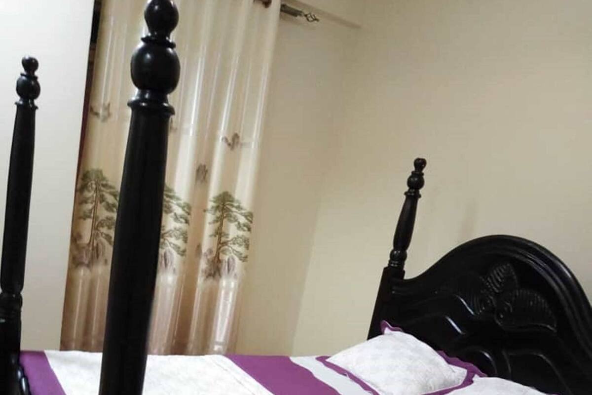 Una cama bien hecha con cabecera negra y colcha morada.