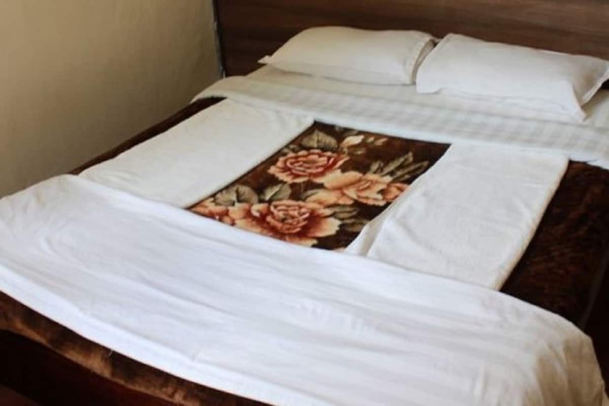 Een bed met een bloemenprint sprei en witte lakens.
