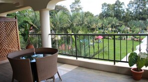 A balcony with wicker furniture, a view of a well-maintained garden, and a white railing. - Gatimene Gardens Hotel (Meru)