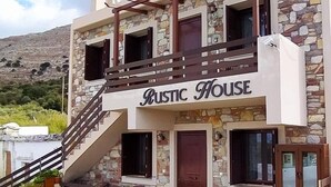 Ein rustikales Haus mit einer Stein-Fassade, einer Holztreppe und einem Balkon.