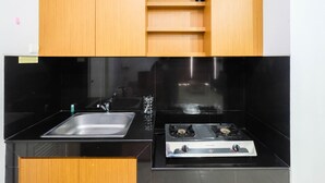 A kitchen with a black countertop, stainless steel sink, and a gas stove.