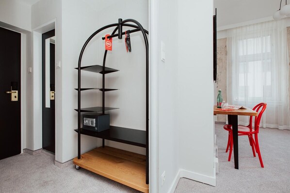 A modern room with a black metal shelving unit, a wooden table, and red chairs. - Hotel Babula am Augarten (Vienna)