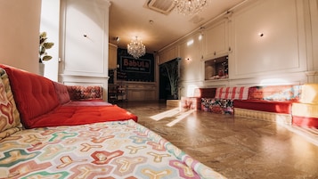 Ampla sala de estar com um sofá vermelho, tapete estampado e um lustre.