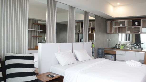 Une chambre d’hôtel moderne avec un grand lit, un bureau équipé d’une machine à café et un miroir.