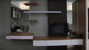 Un salon moderne doté d’un téléviseur à écran plat, d’étagères en bois et d’une bibliothèque intégrée.