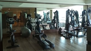 A gym with various exercise equipment, including treadmills, elliptical machines, and weight machines. - City View Studio Apartment at Tamansari La Grande (Bandung)