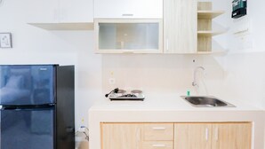 Et moderne køkken med lyse skabe, et sort køleskab, en indbygget mikrobølgeovn og en vask i rustfrit stål.