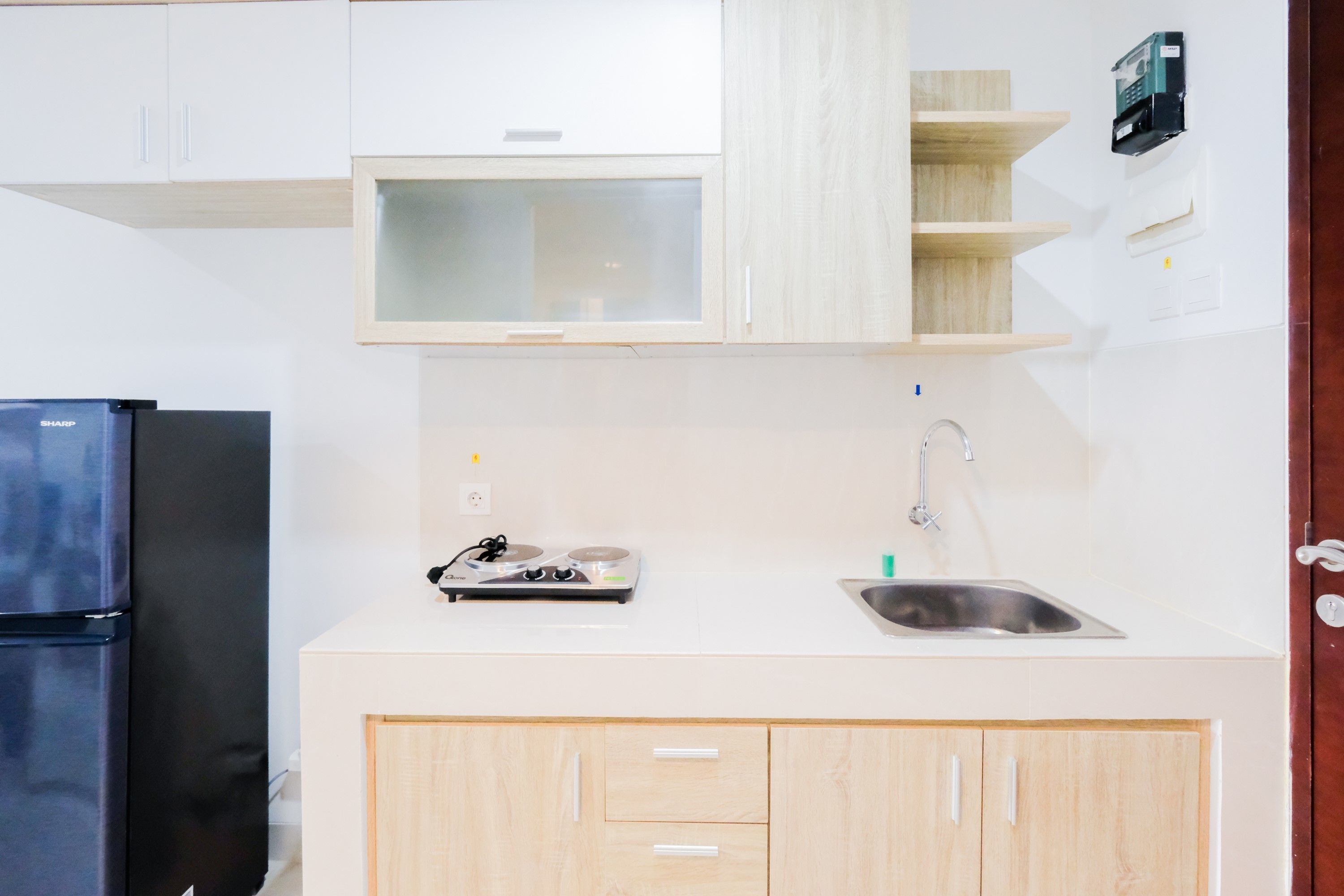 Eine moderne Küche mit weißen Schränken, einem schwarzen Kühlschrank, einer eingebauten Mikrowelle und einer Spüle aus Edelstahl.