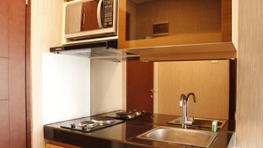 A compact kitchen with a black countertop, stainless steel sink, and a microwave above the stove. - Classic 2BR Apartment At Gateway Pasteur near Exit Toll (Cimahi)
