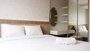 A modern hotel room with a large bed, a built-in vanity, and a full-length mirror. - Classic 2BR Apartment At Gateway Pasteur near Exit Toll (Cimahi)