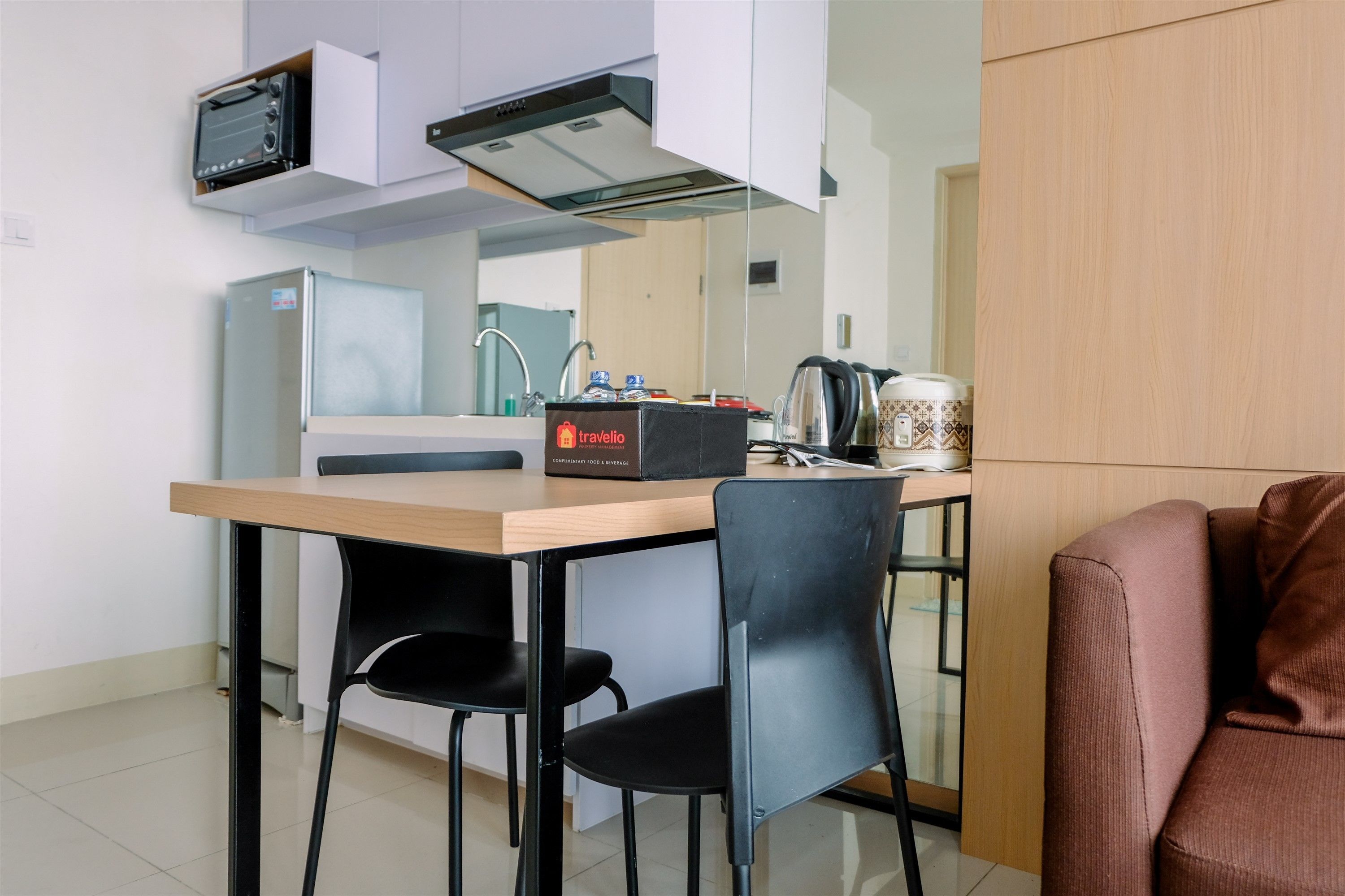 A compact kitchen with a microwave, toaster, and coffee maker. There is a small table with two chairs and a cabinet with a travel-sized refrigerator.