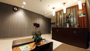 A reception area with a wooden desk, a clock on the wall, and a cabinet with glass doors.