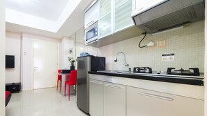 A modern kitchen with white cabinets, a stainless steel refrigerator, a microwave, and a gas stove.
