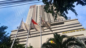 A multi-story building with several flags, including a flag with "JAL" and "RENAULT" logos, and a sign for "GOLD'S GYM".