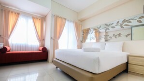A hotel room with a large bed, a red sofa, and a nightstand.