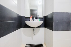 Bathroom features a white sink, mirror, and dark gray tile walls, along with a black rubber mat on the floor.