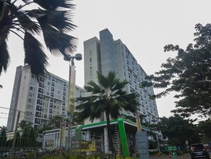 Experience the sleek entrance of this high-rise building, featuring a green awning and modern glass and concrete design.