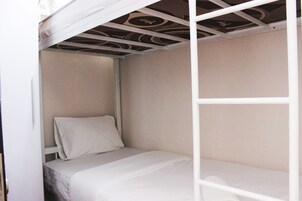 Una cama individual con colchón blanco y cabecera, un techo con diseño decorativo y una pared blanca.