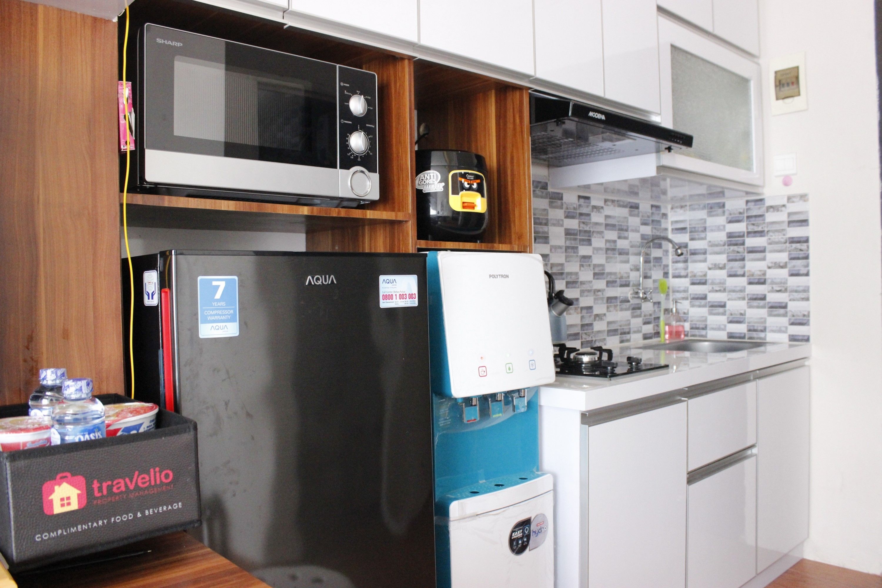 A compact kitchen with a microwave, refrigerator, and water dispenser.
