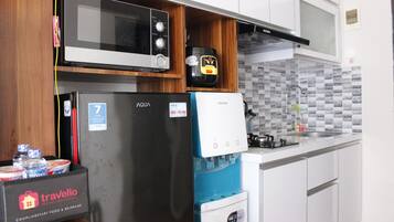 A compact kitchen with a microwave, refrigerator, and water dispenser.