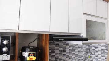 A kitchen with white cabinets, a microwave, a coffee maker, and a kettle.
