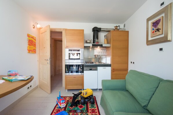 Un espacio habitable compacto con kitchenette, un sofá verde y un juguete de niño en el suelo.