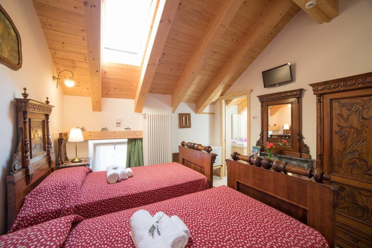 A room with two beds, wooden furniture, a television, and a window with a view.