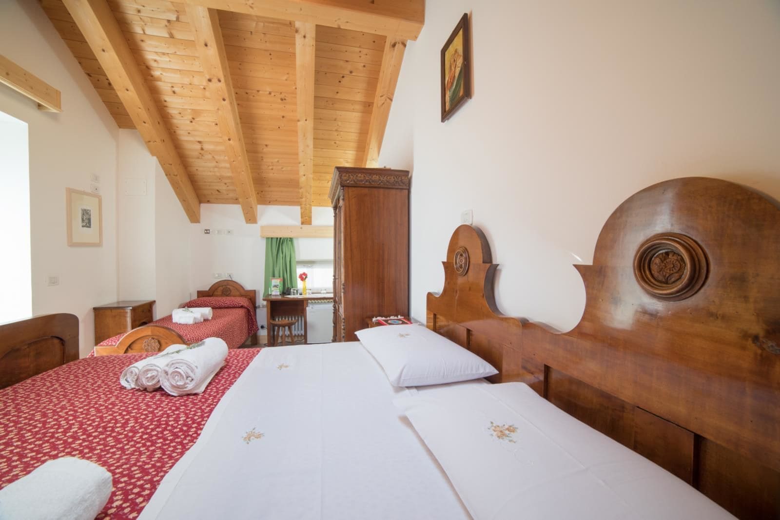 A hotel room with two beds, wooden headboards, and a small desk with a chair.