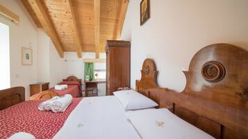 A hotel room with two beds, wooden headboards, and a small desk with a chair.