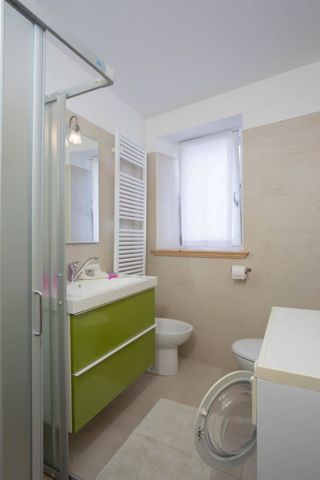 A bathroom with a shower, sink, toilet, and a window.
