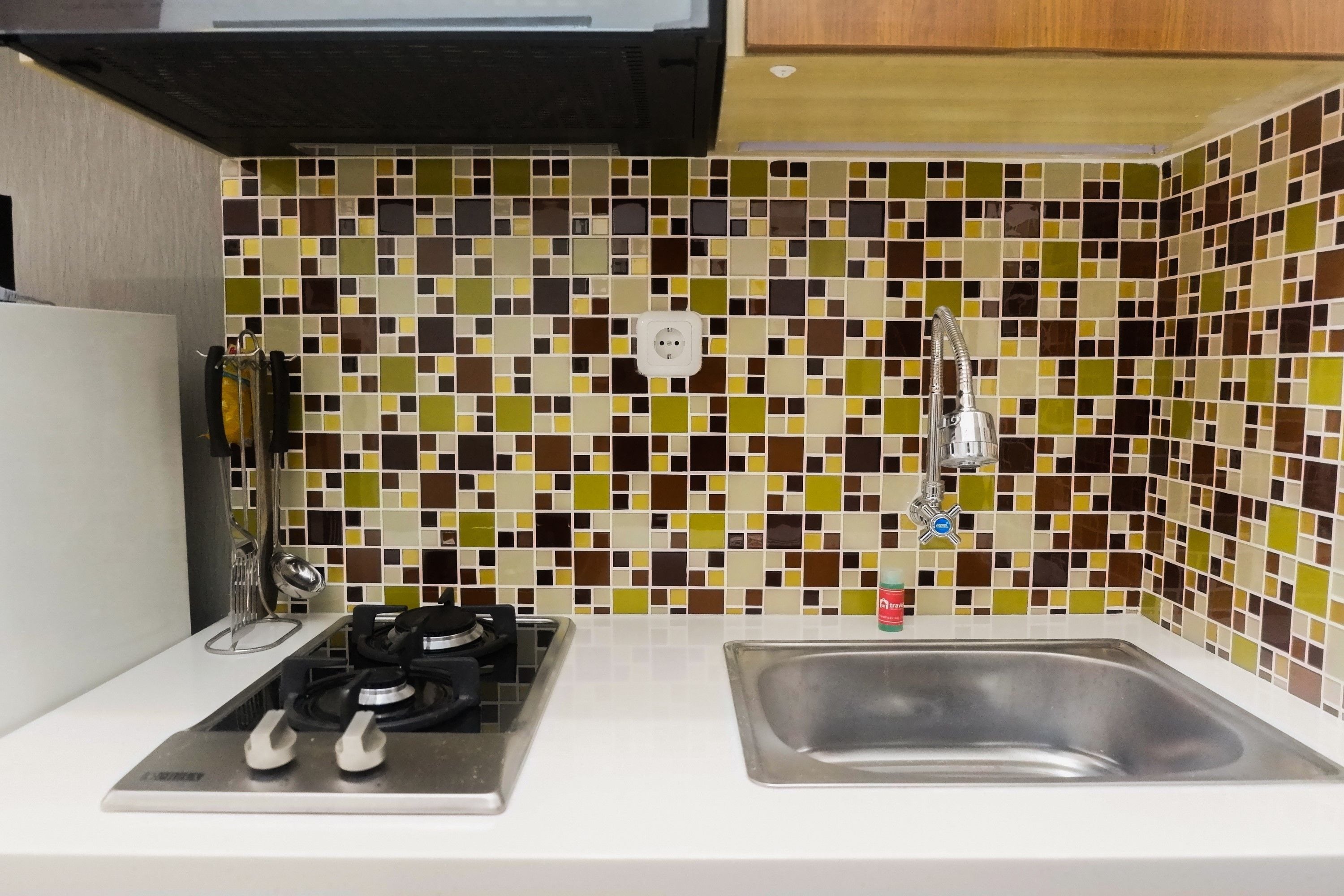 A kitchen with a gas stove, a sink, and a tiled backsplash.