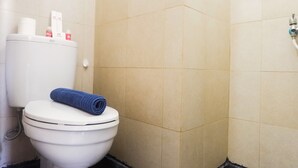 A bathroom with a toilet, a towel, and a toilet paper holder. - Comfy Studio Apartment at Menara Rungkut (Surabaya)