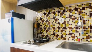 A kitchen with a gas stove, a sink, and a colorful mosaic backsplash. - Comfy Studio Apartment at Menara Rungkut (Surabaya)
