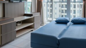 A modern bedroom with a bed, a TV, and a balcony with a city view. - Cozy 1BR at Casa De Parco Apartment (Pagedangan)