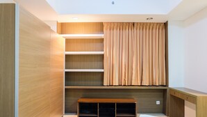 A hotel room with a bed, a wooden bench, built-in shelves, and a curtain. - Cozy and Elegant 2BR Kemang Village Apartment (Jakarta)