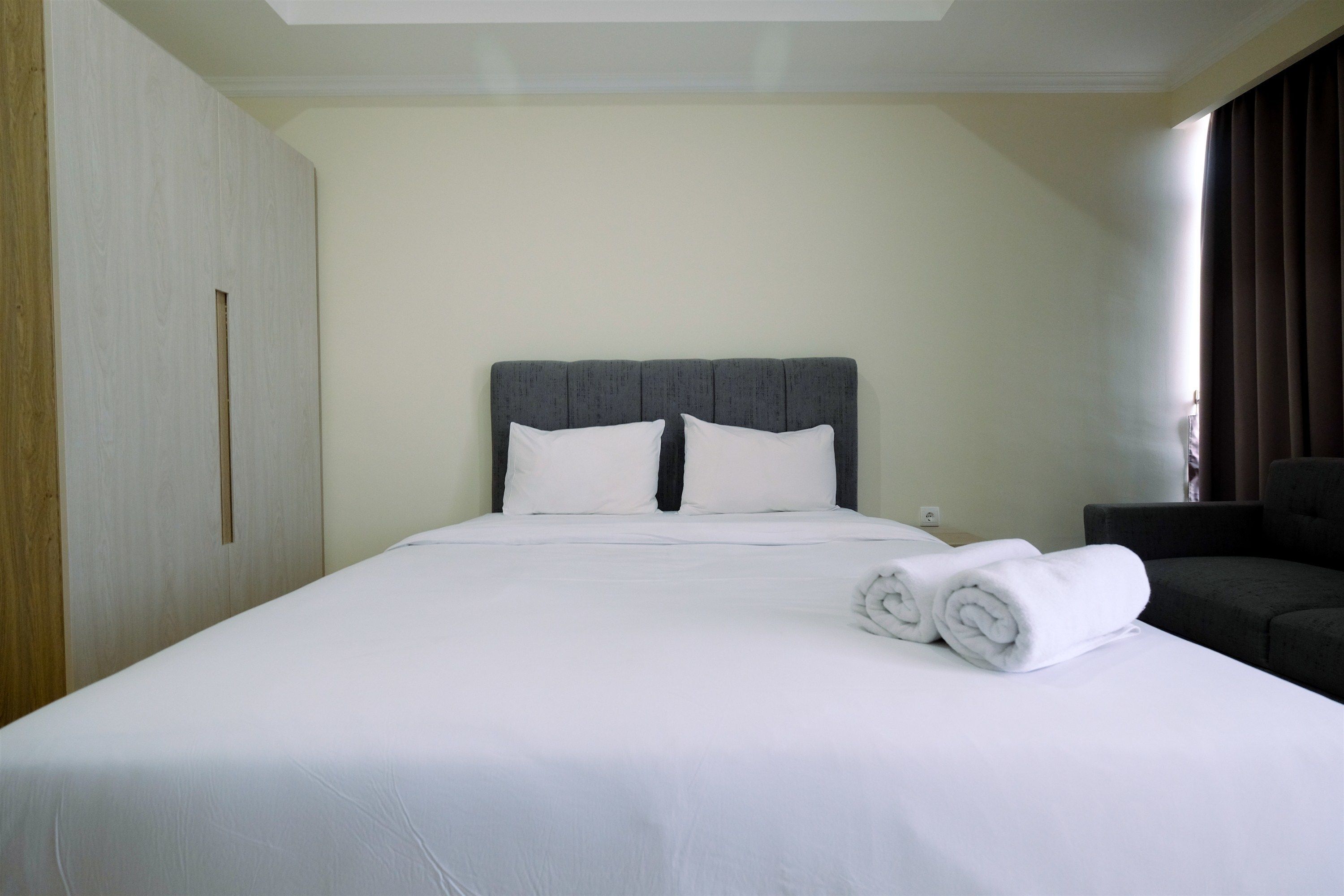 A hotel room with a large bed, a headboard, and a seating area with a chair.