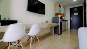 Cozinha moderna com televisão de tela plana, armários de madeira, geladeira e área de refeições com cadeiras brancas.