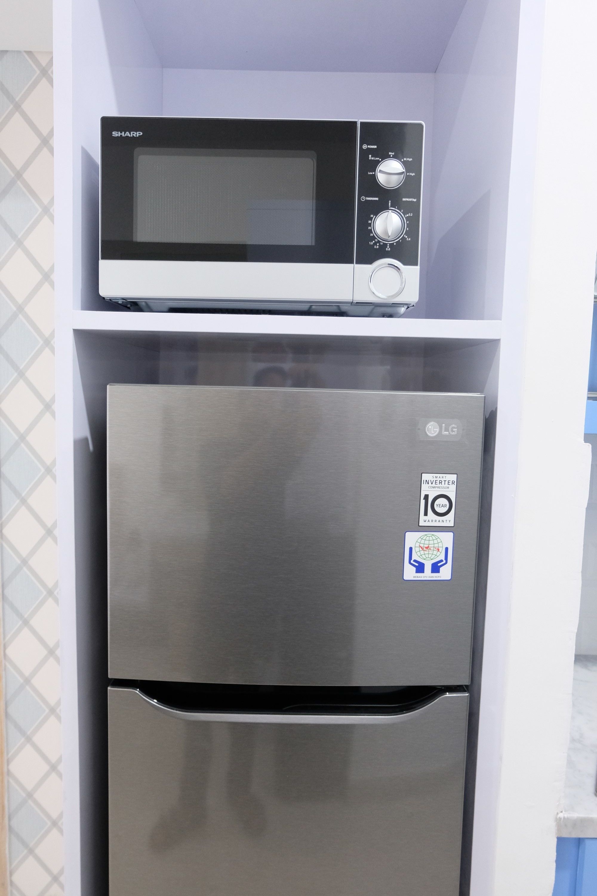 Eine kleine Küche mit einer Mikrowelle auf einem Edelstahl-Kühlschrank.
