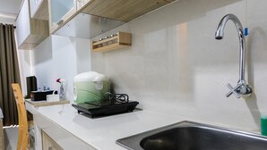 Een moderne keuken met een roestvrijstalen spoelbak, een koffieapparaat en een houten plank boven het aanrecht.