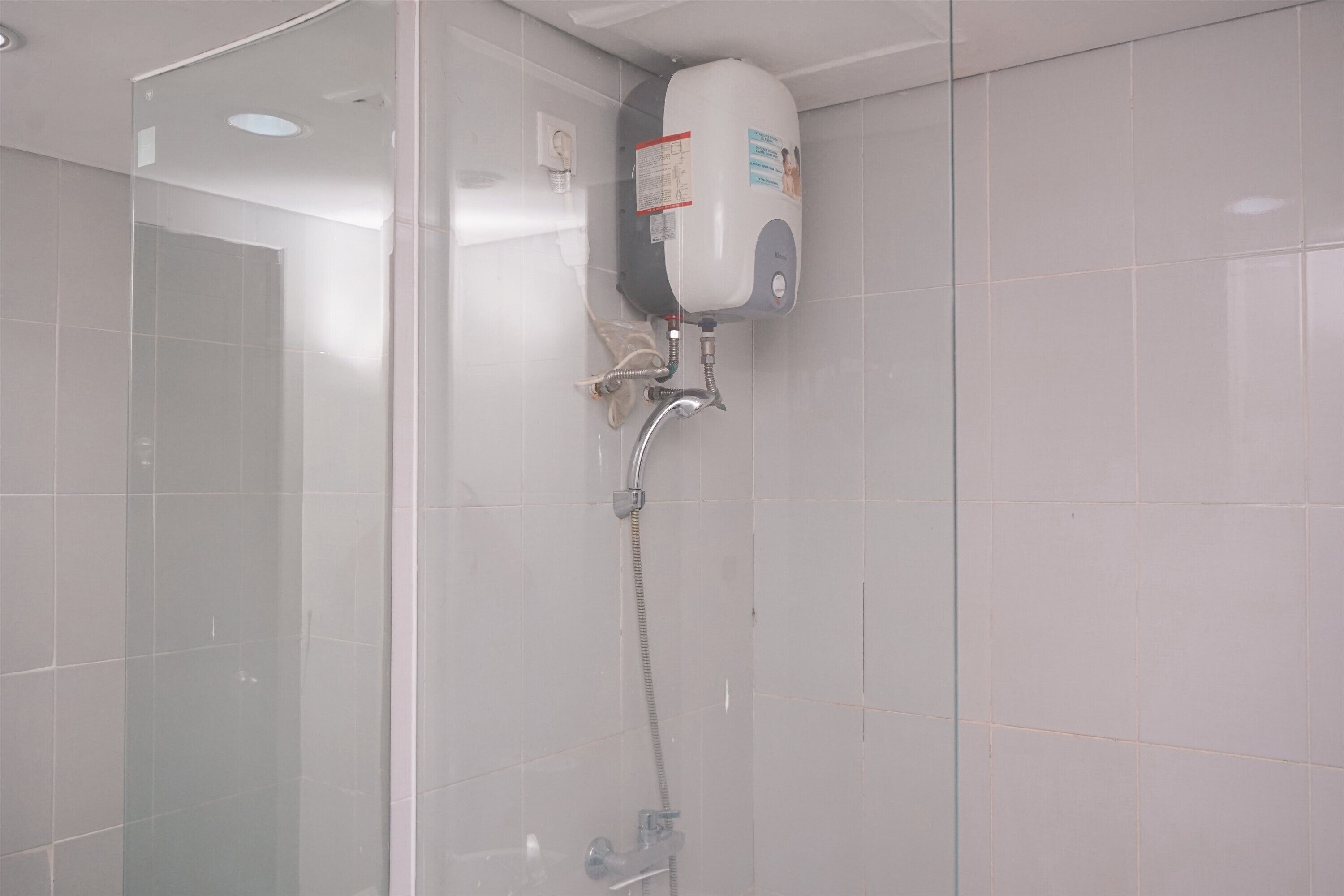 Ducha con cabezal de ducha de mano y dispensador de jabón de pared.