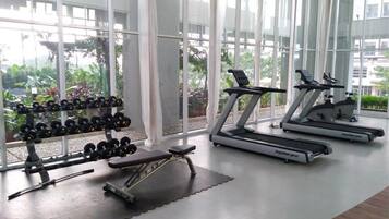 A gym with treadmills, dumbbells, and a bench.