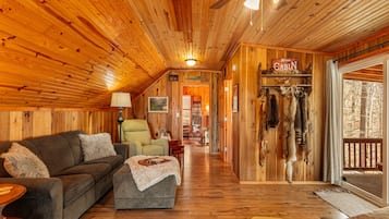 Relax in this cabin with a comfortable sofa, armchair, and coffee table, surrounded by natural views and rustic charm.