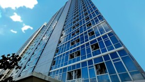 A tall, modern building with a glass facade and a clear blue sky in the background.