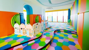 A brightly colored play area with hexagonal patterned flooring and white playhouses.