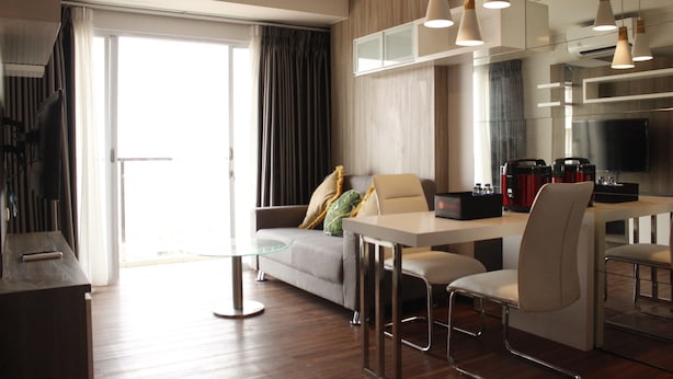 A modern kitchen with a dining area, a sofa, and a glass table. - Gorgeous 2BR Apartment at Gateway Pasteur near Exit Toll (Cimahi)