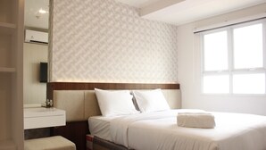 A neatly made bed with white bedding, a wooden headboard, and a bedside table with a lamp. - Gorgeous 2BR Apartment at Gateway Pasteur near Exit Toll (Cimahi)