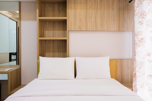 Ein modernes Hotelzimmer mit einem hölzernen Kopfteil, einem großen Spiegel und einem Bett mit weißen Bettwäsche.